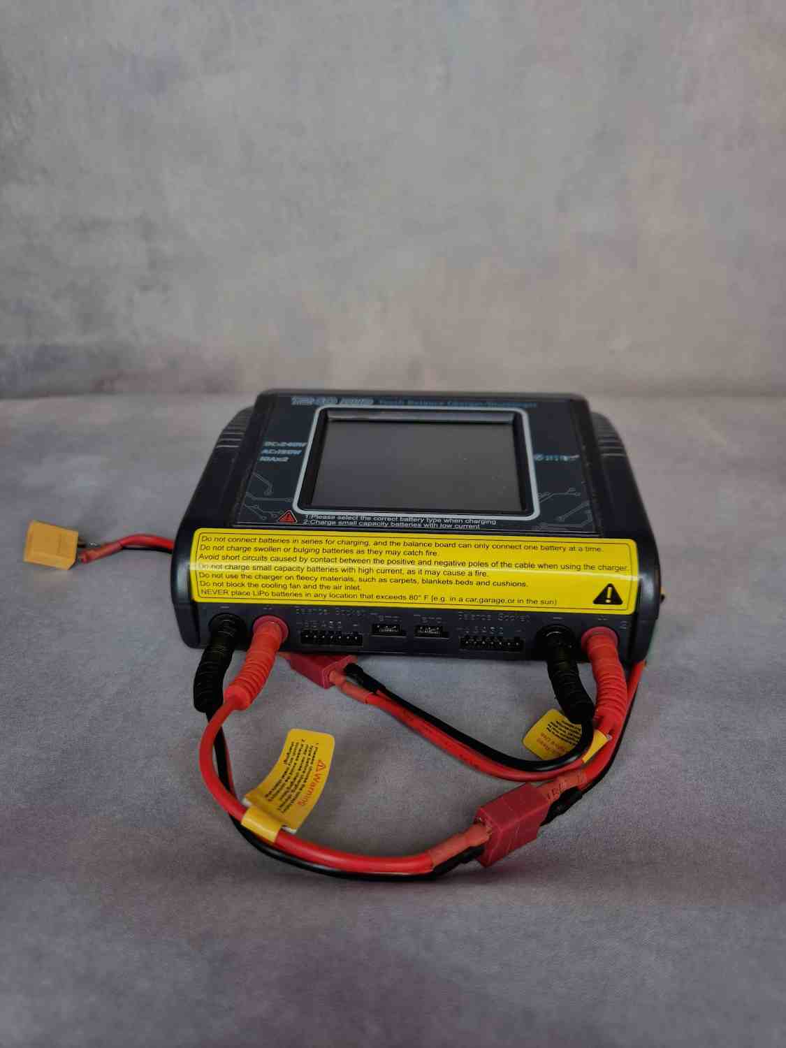 Battery charger with red and black cables on a gray surface